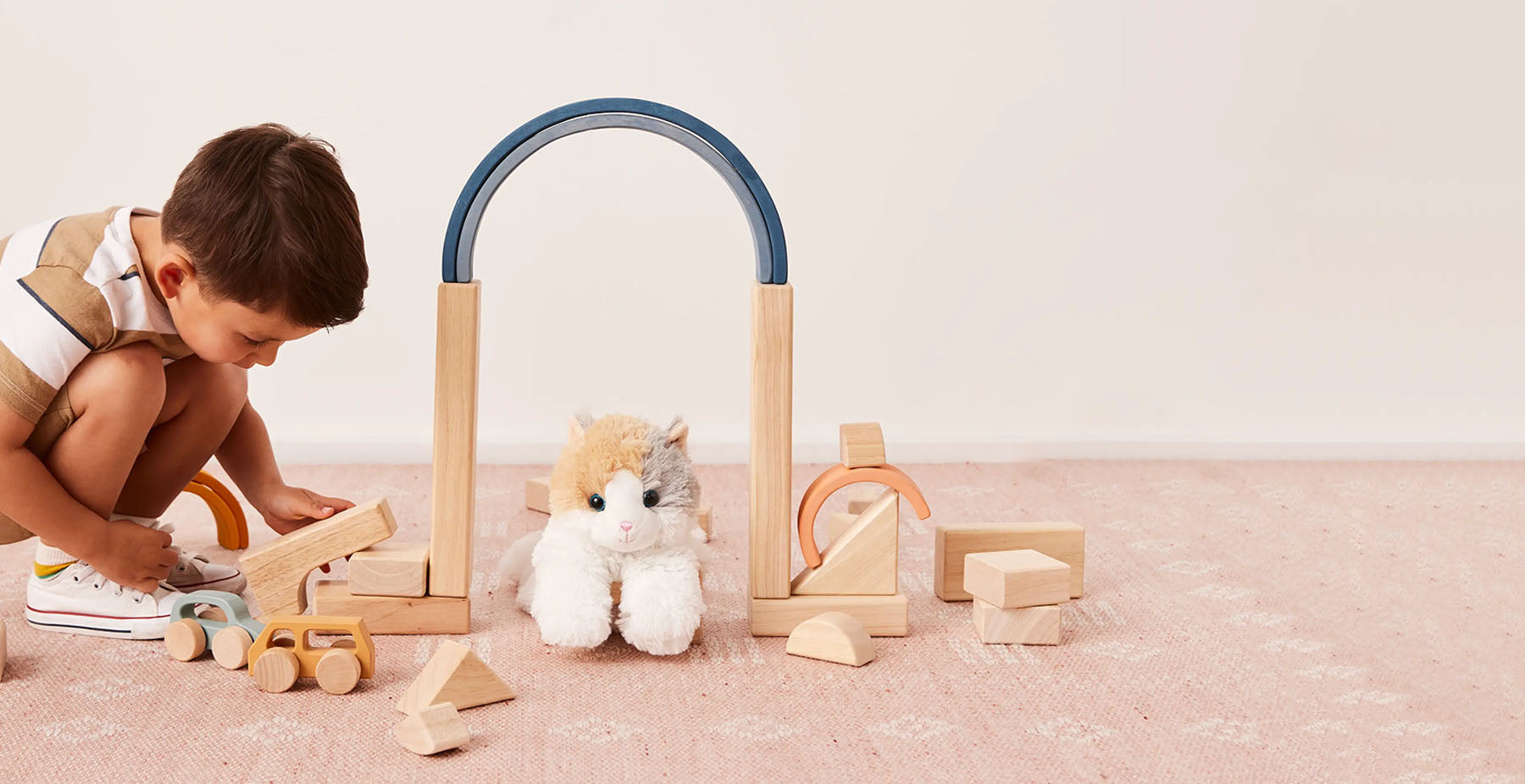 little boy playing with cat stuffed animal warmies