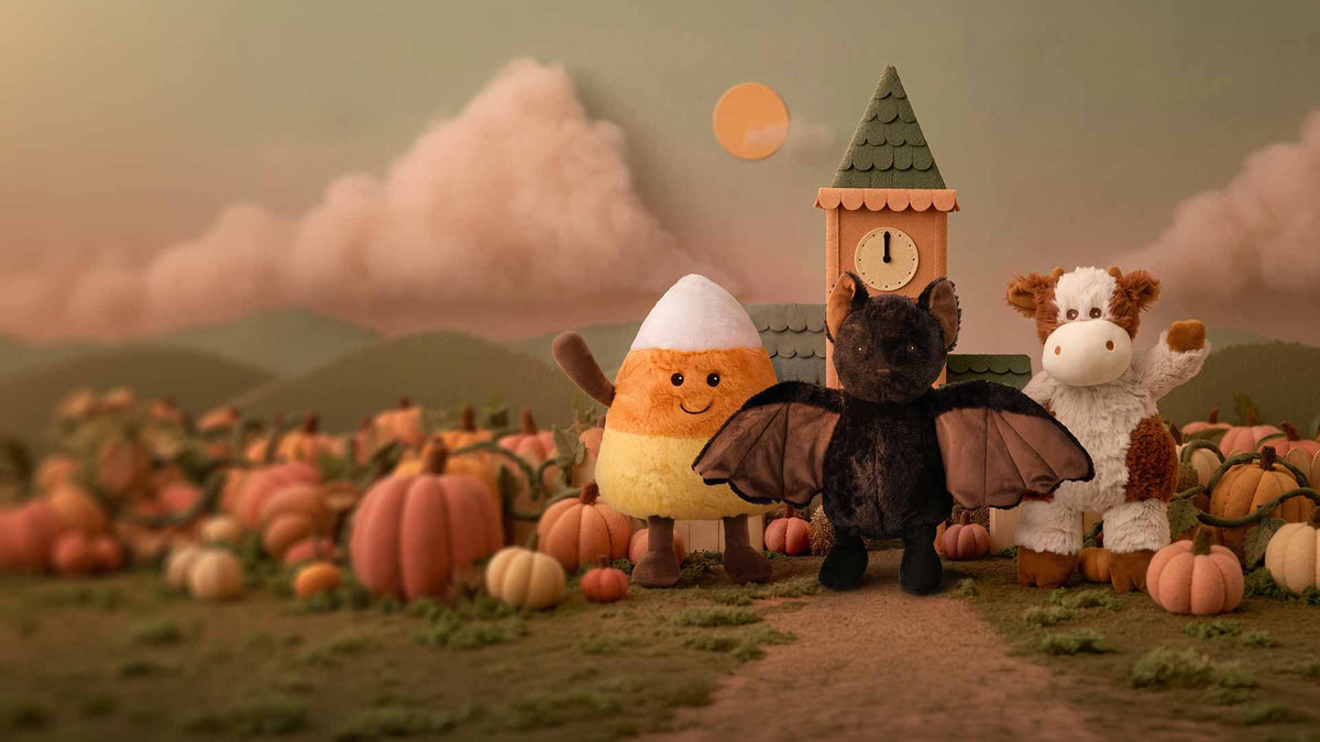 Candy corn, bat and cow Warmies plush in a cozy fall pumpkin patch