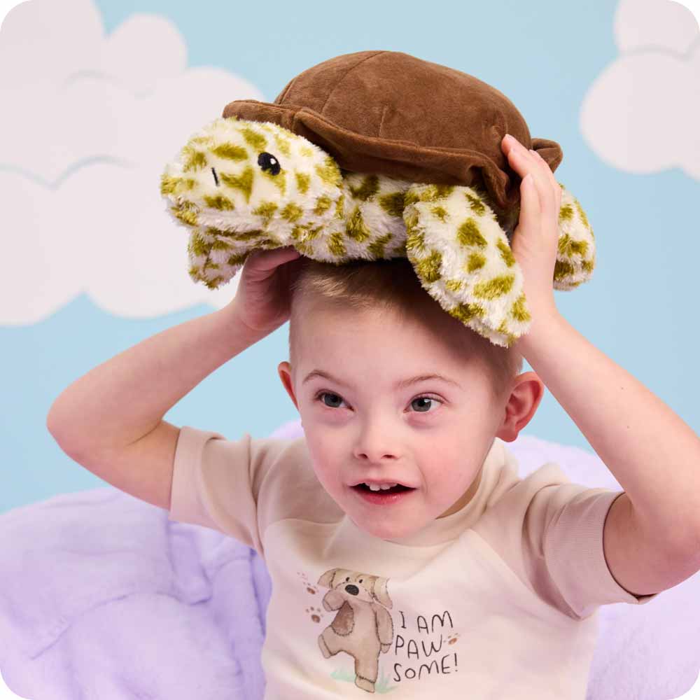 Little boy holding a Turtle Warmies on his head.