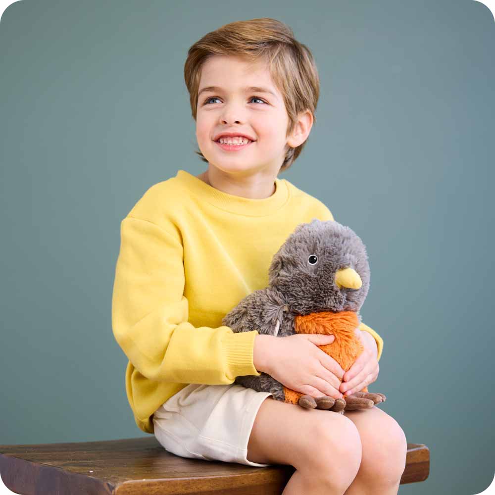 Little boy sitting on a chair holding a American Robin Warmies in his lap.