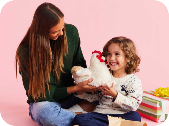 Woman gifting Chicken Warmies to a smiling child.