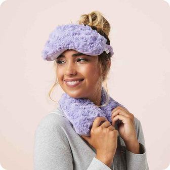 Woman smiling while wearing Microwavable Curly Purple Warmies Eye Mask 