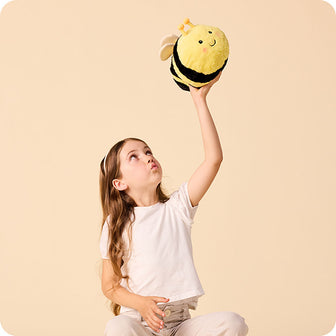 girl holding up a bee stuffed animal warmies