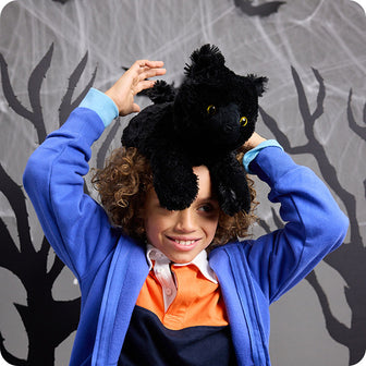 boy with black cat stuffed animal on his head