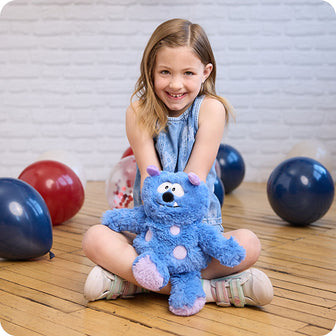 girl holding blue monster stuffed animal
