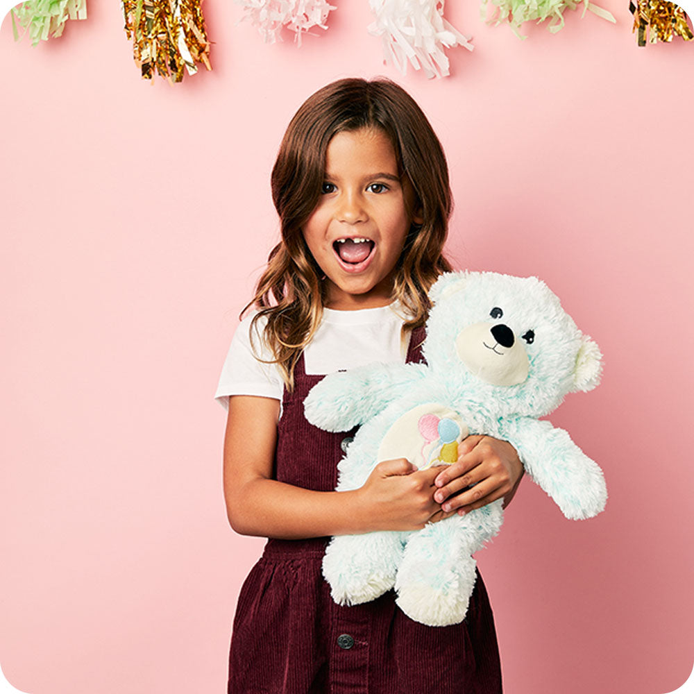 party setting lifestyle little girl holding celebration bear stuffed animal