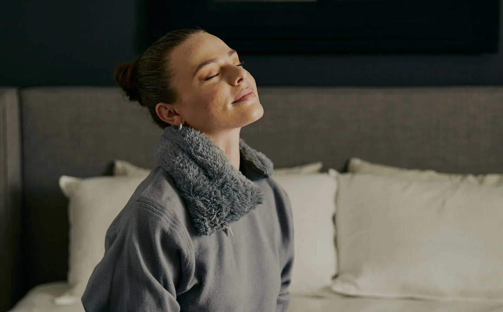 Woman with closed eyes wearing Gray Warmies Neck Wrap. 