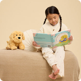 girl reading Golden Dog's Magical Adventure warmies book with golden dog stuffed animal at her side