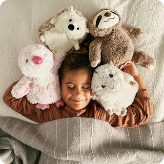 girl sleeping with 4 warmies stuffed animals hedgehog