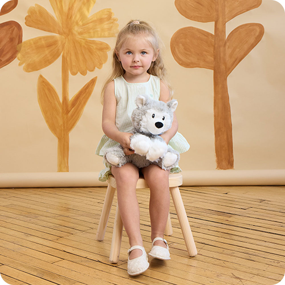 girl holding a warmies husky stuffed animal