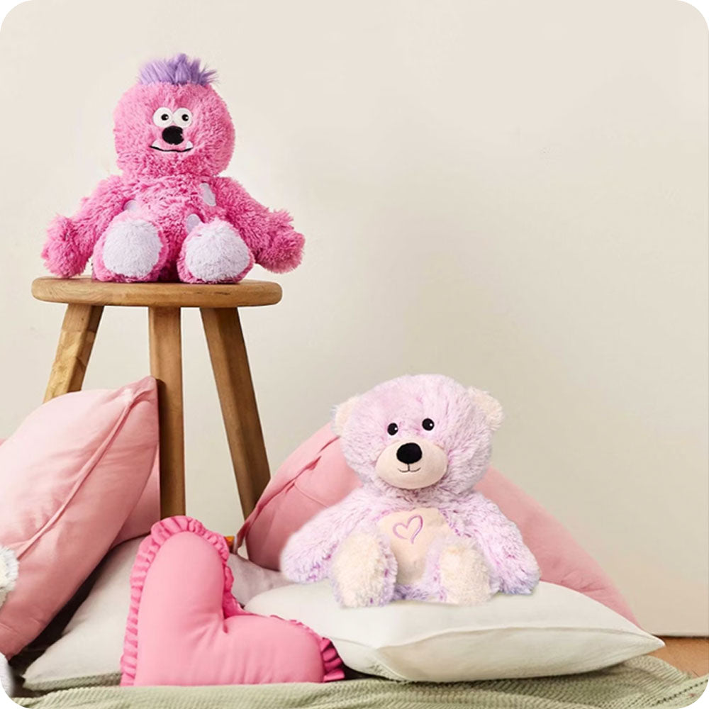 pink bear stuffed animal on pillow pile