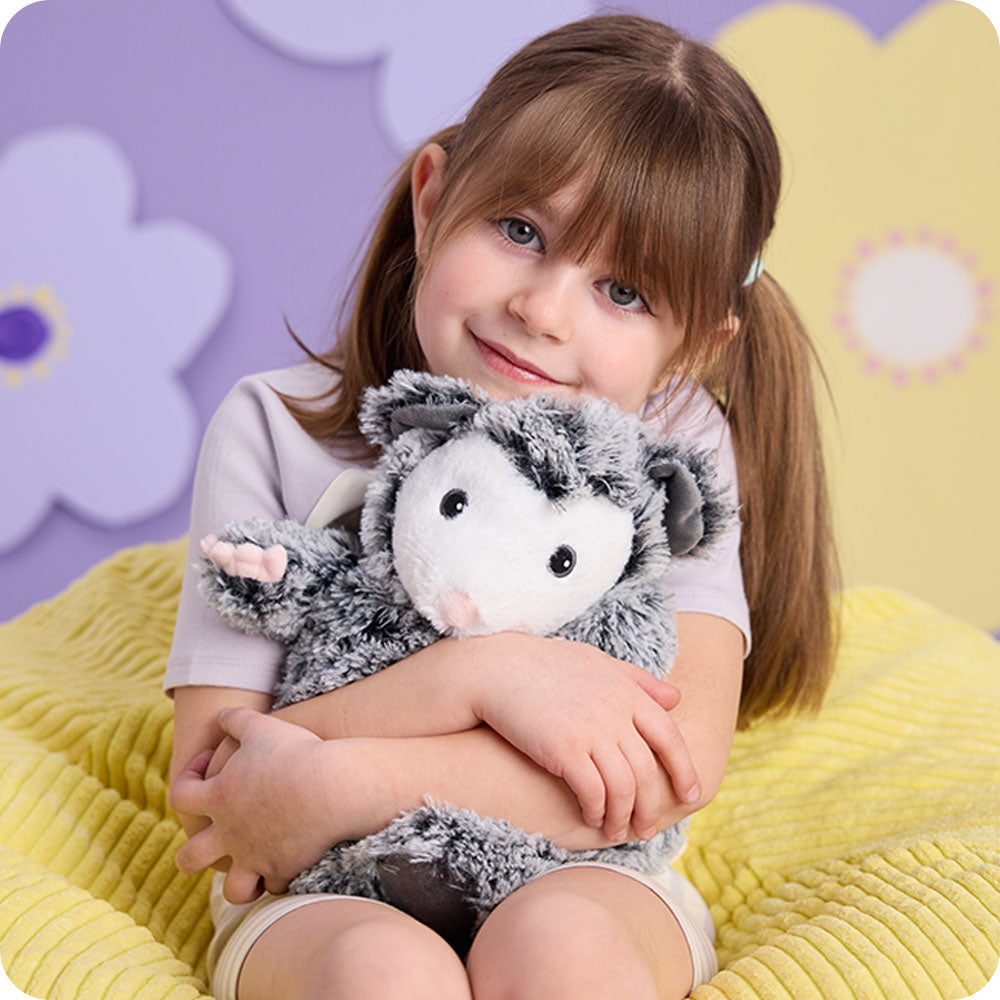 girl hugging opossum stuffed animal warmies