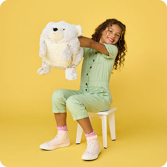 girl holding out supersized bear stuffed animal warmies