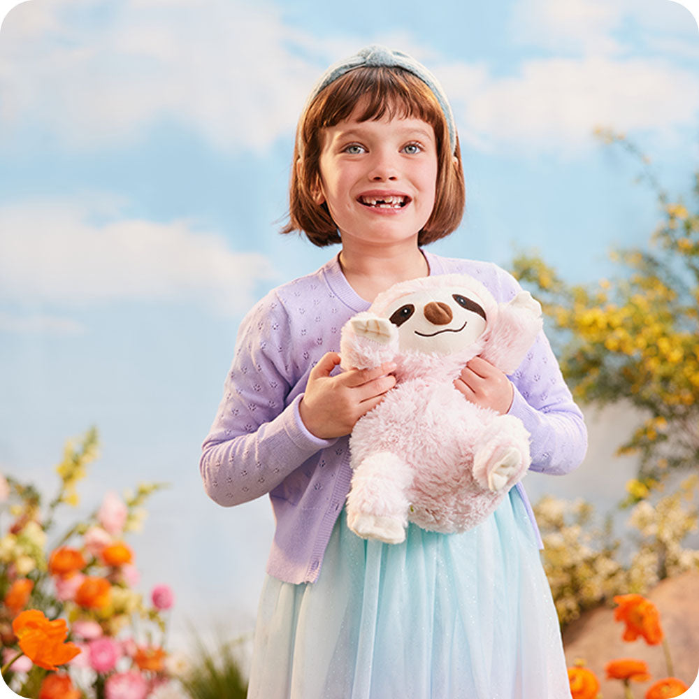 little girl hugging pink sloth stuffed animal warmies