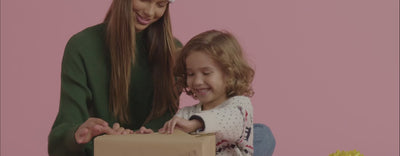 A video of a young girl helping her little brother open up presents and playing with Warmies.