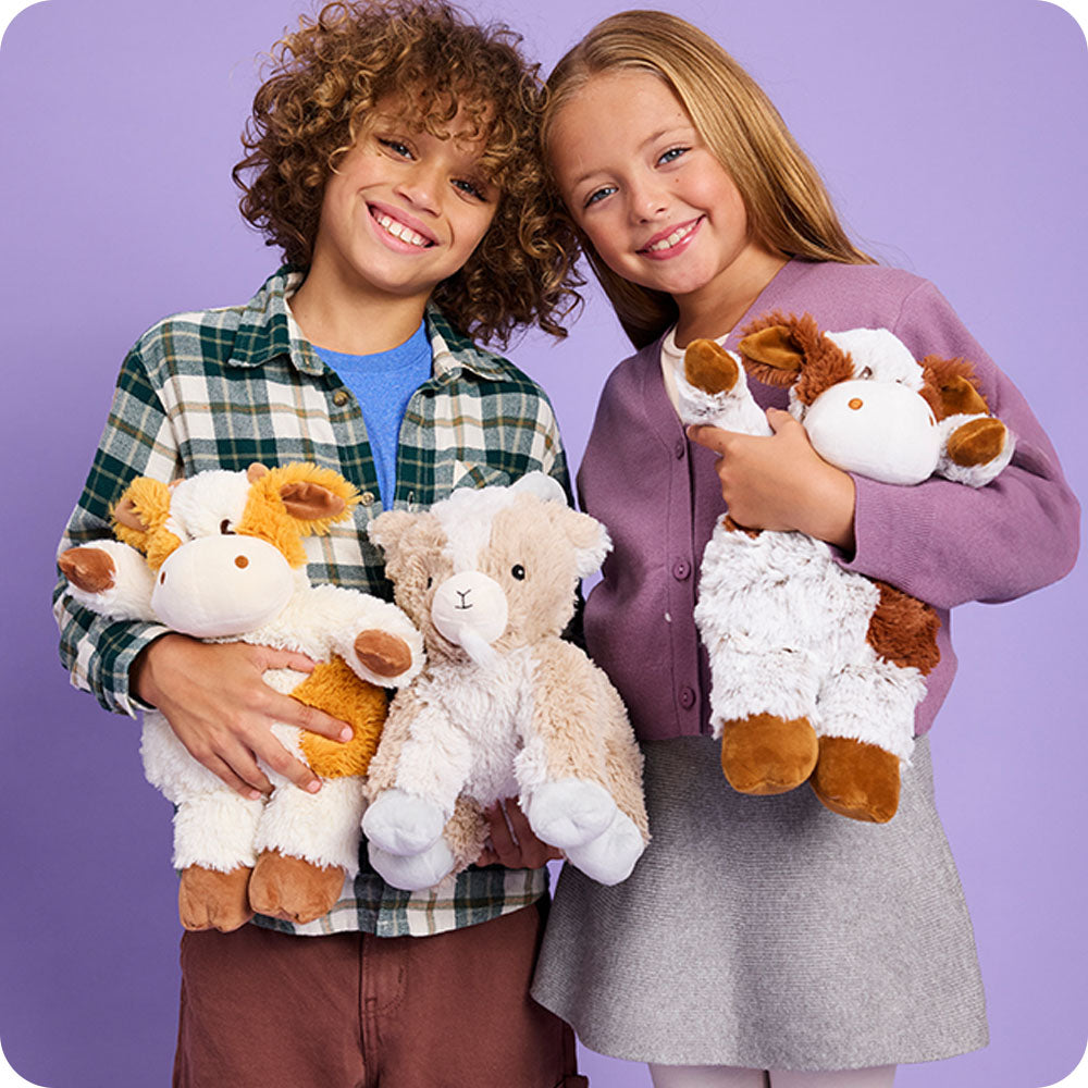 boy and girl holding pumpkin spice cow stuffed animal warmies