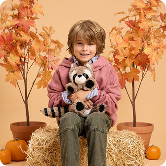 boy holding raccoon stuffed animal in autumn setting