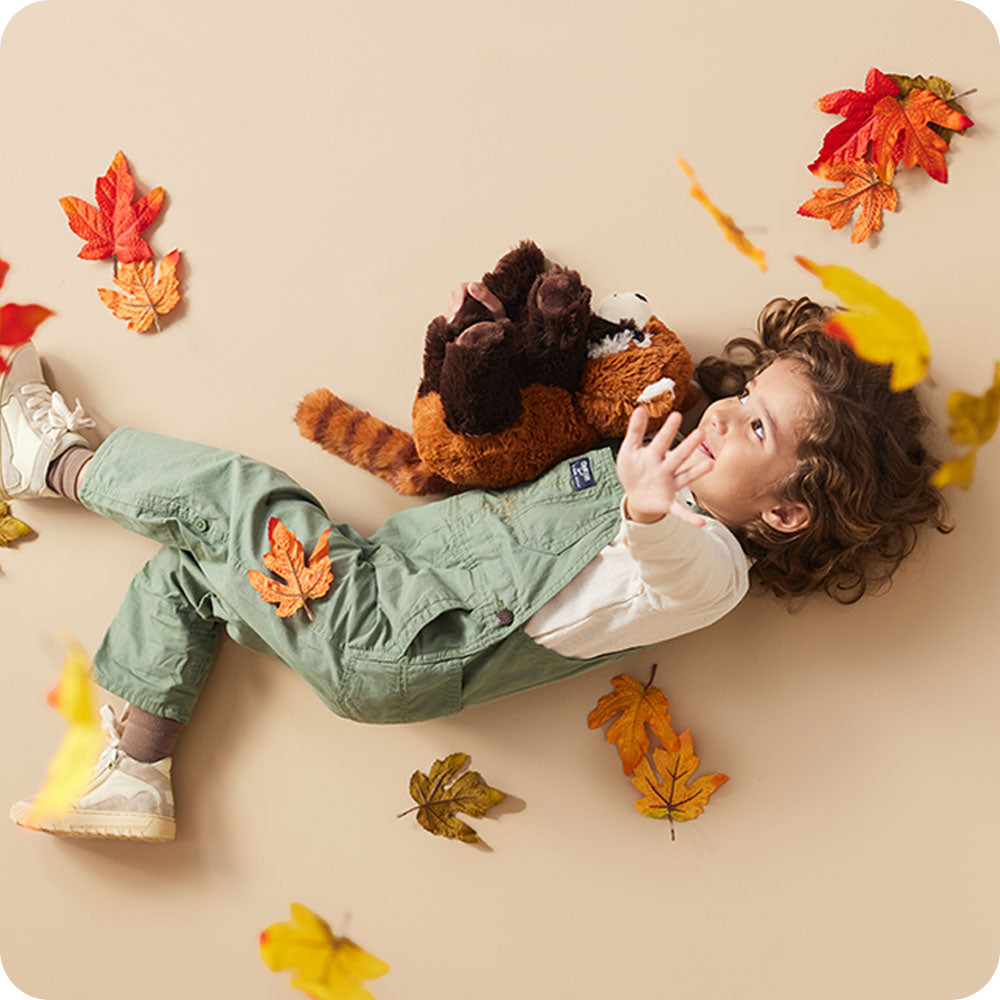 girl holding red panda stuffed animal warmies in autumn setting