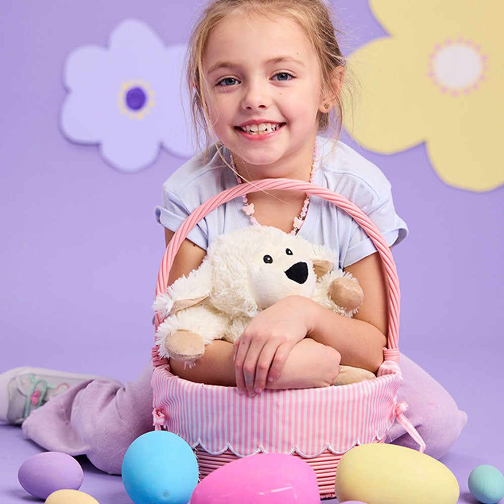 girl holding sheep stuffed animal in easter basket