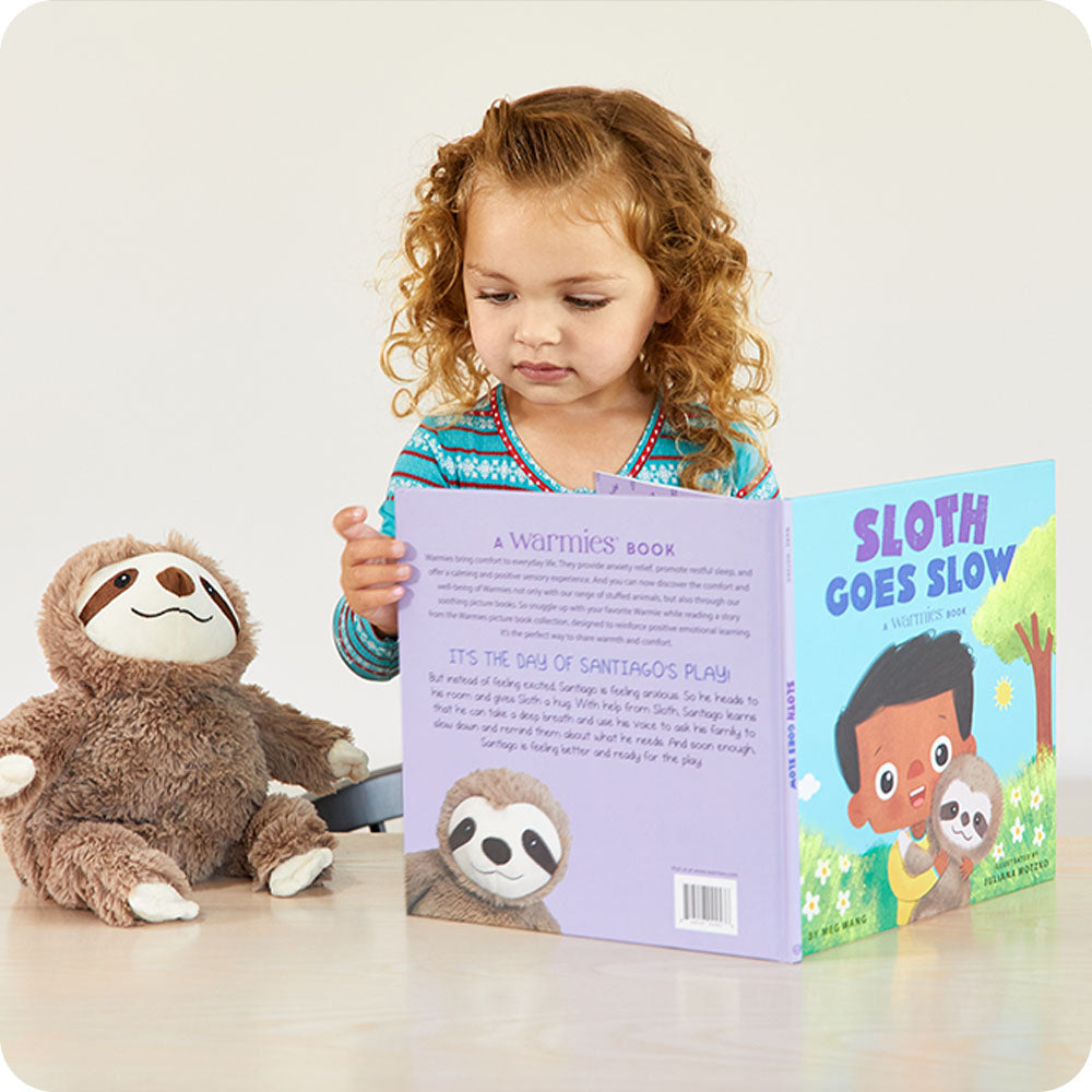 toddler reading warmies Sloth Goes Slow book with sloth stuffed animal