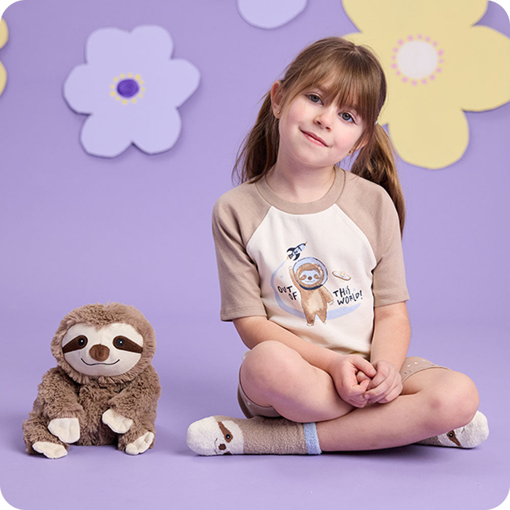 sloth stuffed animal and girl wearing sloth socks and pajamas