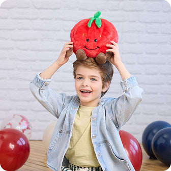 boy holding strawberry stuffed animal warmies on his head