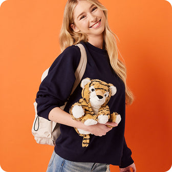 girl holding tiger stuffed animal warmies