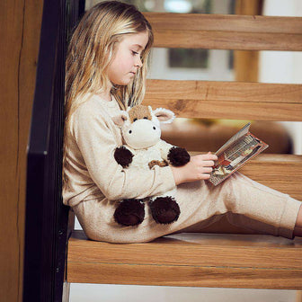 Little girl reading a book with Cute Weighted Lavender Scented Cow Stuffed Animal Heating Pad Warmies