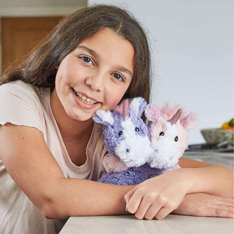 Girl smiling while hugging Heated Unicorn Hugs Plush Warmies