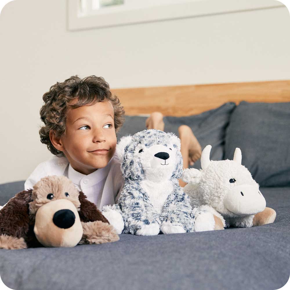 Little boy laying down with Soft Warm Weighted Snow Leopard Plush Warmies