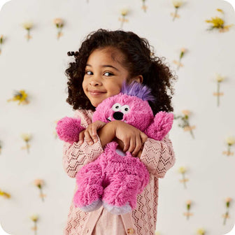 Little girl hugging her Cute Weighted Lavender Scented Pink Monster Stuffed Animal Heating Pad Warmies
